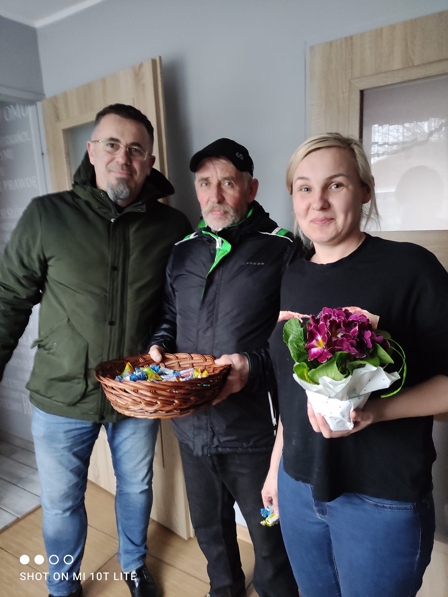 wójt i członek rady sołeckiej obdarowuja kwiatami i słodyczami mieszkanki moszowic
